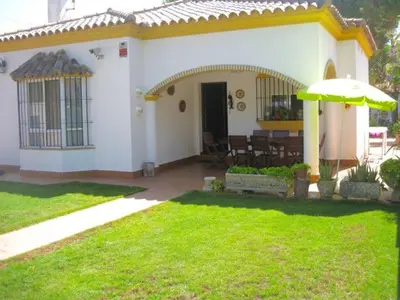 a white house with an umbrella in a yard at Recreo de Pilant - Holiday Chiclana in Chiclana de la Frontera
