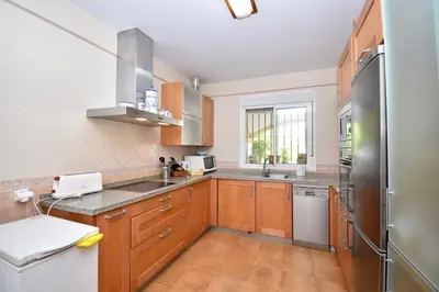 a kitchen with wooden cabinets and a stainless steel refrigerator at Recreo de Pilant - Holiday Chiclana in Chiclana de la Frontera