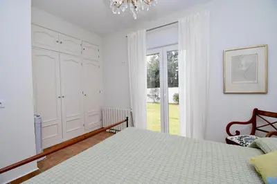 a white bedroom with a bed and a window at Leonita in Chiclana de la Frontera