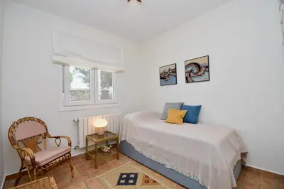 a bedroom with a bed and a chair and a window at Leonita in Chiclana de la Frontera