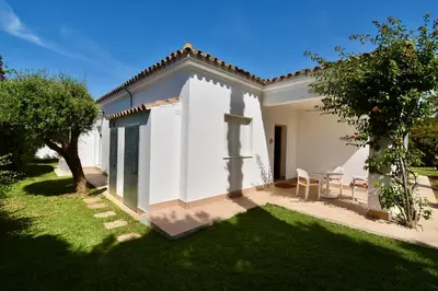 a white house with a green yard with a grass yard at Leonita in Chiclana de la Frontera