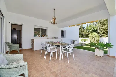 a dining room and living room with a table and chairs at Leonita in Chiclana de la Frontera