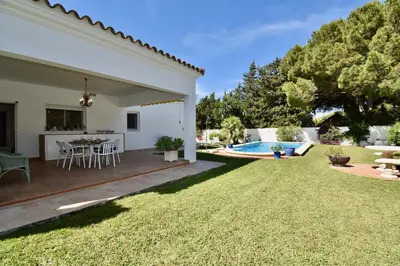 a backyard with a table and chairs and a pool at Leonita in Chiclana de la Frontera