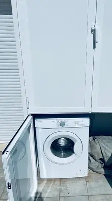 a washer and dryer under a white cabinet at ATICO CALLE FARIÑAS in Sanlúcar de Barrameda