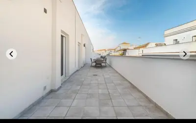 an empty corridor of a white building with a bench at ATICO CALLE FARIÑAS in Sanlúcar de Barrameda