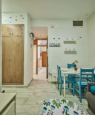 a living room with a table and blue chairs at The Sailors House Ha in Cádiz