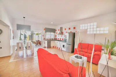a living room with a red couch and a kitchen at VILLA YUCA CON PISCINA PRIVADA en CONIL DE LA FRONTERA in Conil de la Frontera