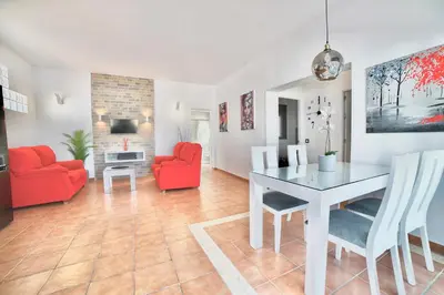a living room with a table and red chairs at VILLA YUCA CON PISCINA PRIVADA en CONIL DE LA FRONTERA in Conil de la Frontera