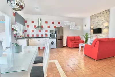 a kitchen and living room with a red chair at VILLA YUCA CON PISCINA PRIVADA en CONIL DE LA FRONTERA in Conil de la Frontera