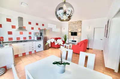 a kitchen and living room with red chairs and a table at VILLA YUCA CON PISCINA PRIVADA en CONIL DE LA FRONTERA in Conil de la Frontera