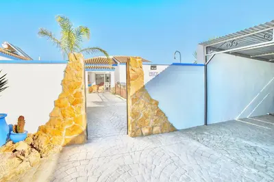 a house with a sliding gate and a palm tree at VILLA YUCA CON PISCINA PRIVADA en CONIL DE LA FRONTERA in Conil de la Frontera