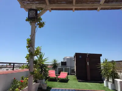 a patio with pink chairs and a grill on a roof at Ático con terraza privada en casa Palacio del Centro Histórico in El Puerto de Santa María