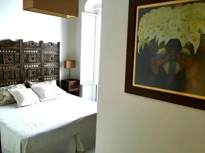 a bedroom with a bed and a painting on the wall at Ático con terraza privada en casa Palacio del Centro Histórico in El Puerto de Santa María