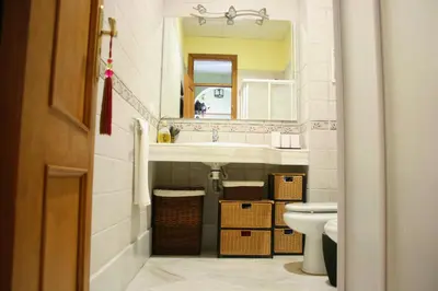 a bathroom with a sink and a toilet and a mirror at Ático con terraza privada en casa Palacio del Centro Histórico in El Puerto de Santa María