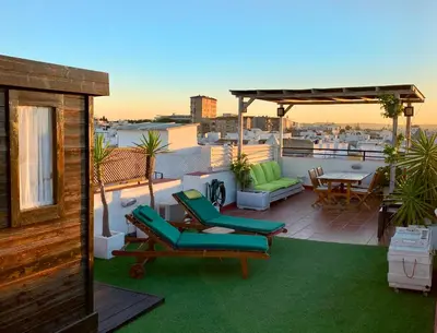 a patio with chairs and a table on a roof at Ático con terraza privada en casa Palacio del Centro Histórico in El Puerto de Santa María