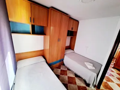 a small room with two beds and wooden cabinets at Apartamento playa y centro de Puerto Real - AC - WiFi in Puerto Real