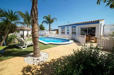 a house with a swimming pool and a palm tree at VILLA BANANERA CON PISCINA PRIVADA en CONIL DE LA FRONTERA in Conil de la Frontera