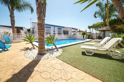 a pool with two lounge chairs and a palm tree at VILLA BANANERA CON PISCINA PRIVADA en CONIL DE LA FRONTERA in Conil de la Frontera