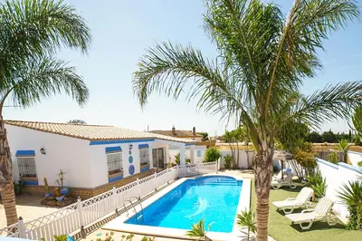 a villa with a swimming pool and palm trees at VILLA BANANERA CON PISCINA PRIVADA en CONIL DE LA FRONTERA in Conil de la Frontera