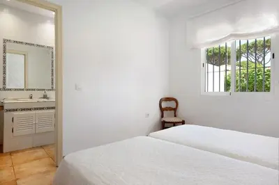 a bedroom with two beds and a sink and a mirror at Villa Escocia, entre pinares y a pie de playa in Roche