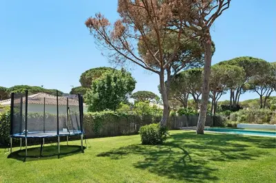 a swing in the grass next to a swimming pool at Villa Escocia, entre pinares y a pie de playa in Roche
