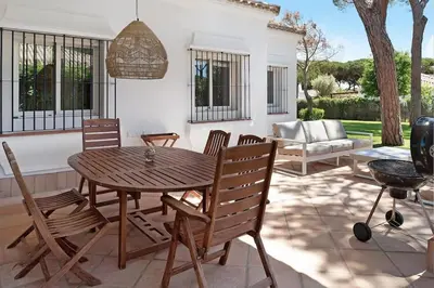 a patio with a wooden table and chairs at Villa Escocia, entre pinares y a pie de playa in Roche