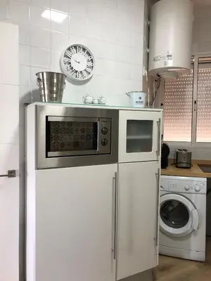 a kitchen with a microwave and a washing machine at El sueño de Lola in Chipiona