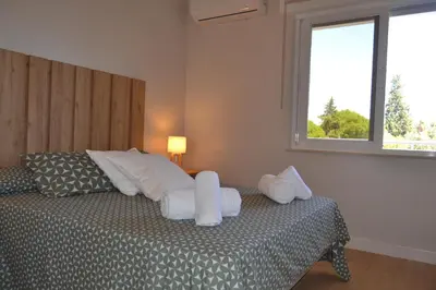 a bedroom with a bed with white pillows and a window at Apartamento Pie de Rey in Jerez de la Frontera