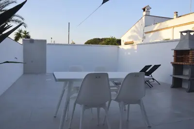 a patio with a table and chairs on a white wall at Villas Noah in Chiclana de la Frontera