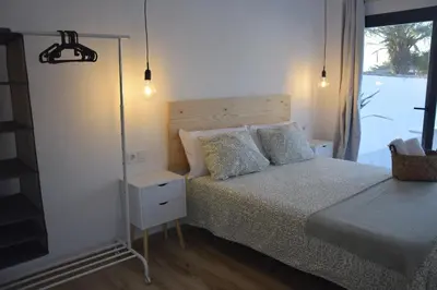 a bedroom with a bed with a night stand and a window at Villas Noah in Chiclana de la Frontera