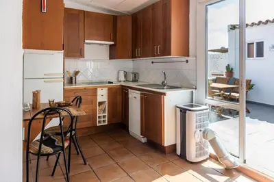 a kitchen with wooden cabinets and a table and a sink at Loft/Attic, Sea Views, Private Terrace in Cádiz