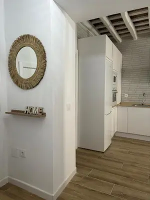 a kitchen with white walls and a mirror on a wall at Herrete Rooms in Medina Sidonia