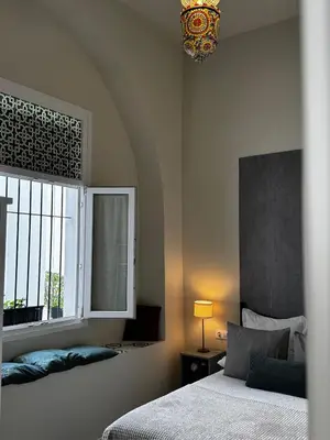 a bedroom with a bed and a window and a chandelier at Karisma Alcázar in Jerez de la Frontera