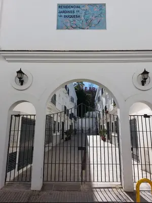 an entrance to a white building with a gate at Apartamento Jardines de la Duquesa con garaje in Sanlúcar de Barrameda