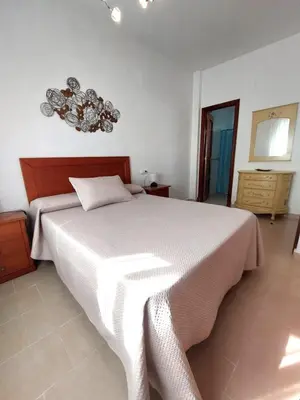 a bedroom with a large bed and a chandelier at Apartamento Jardines de la Duquesa con garaje in Sanlúcar de Barrameda