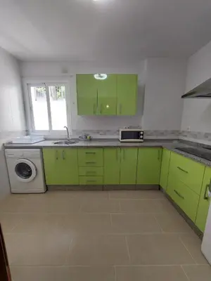 a kitchen with green cabinets and a dishwasher at Apartamento Jardines de la Duquesa con garaje in Sanlúcar de Barrameda