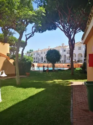 a green yard with trees and a building at Apartamento en Residencial la Caracola en playa la Barrosa in Novo Sancti Petri