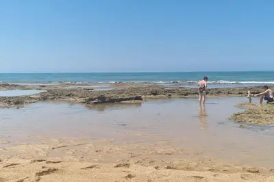 a group of people standing in the water at the beach at Apartamento en Residencial la Caracola en playa la Barrosa in Novo Sancti Petri