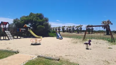 a playground with swings and slides in the sand at Costa Ballena Casa, pie playa y golf in Costa Ballena