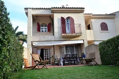 a house with two chairs and a table in the yard at Costa Ballena Casa, pie playa y golf in Costa Ballena