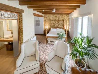 a bedroom with a bed and two white chairs at Hotel Argantonio in Cádiz