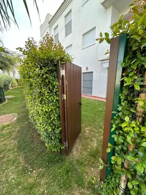 a privacy fence with a wooden gate in front of a building at LA CASA DE LOS PATOS Jardines del lago in Costa de Sanlúcar