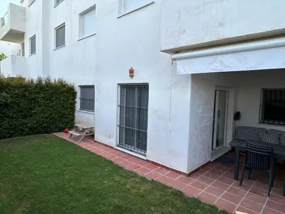 a white building with two windows and a patio at LA CASA DE LOS PATOS Jardines del lago in Costa de Sanlúcar