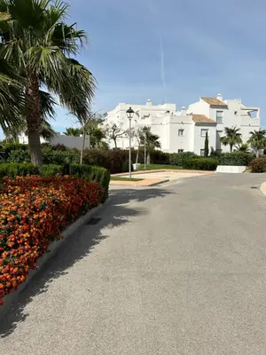 a street with flowers and palm trees in front of a building at LA CASA DE LOS PATOS Jardines del lago in Costa de Sanlúcar
