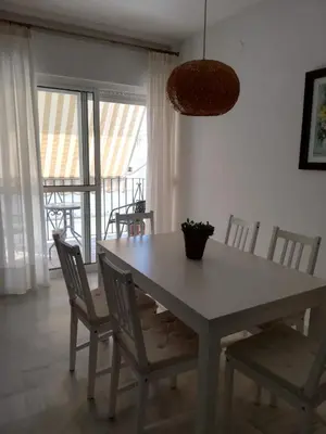 a dining room with a white table and chairs at El piso de Amelia in Sanlúcar de Barrameda