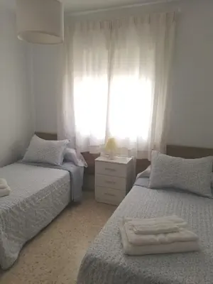 a bedroom with two beds and a window at El piso de Amelia in Sanlúcar de Barrameda