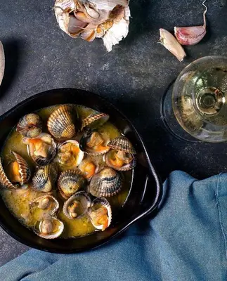 a cast iron skillet filled with clams on a table at Cabildo 3 in Sanlúcar de Barrameda