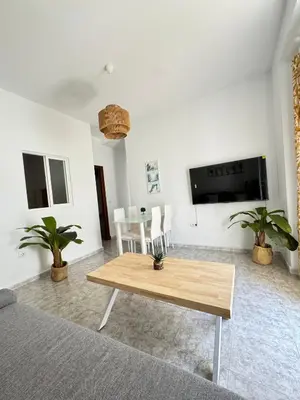 a living room with a table and a tv at Cabildo 3 in Sanlúcar de Barrameda