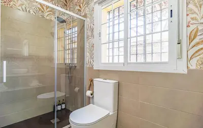 a bathroom with a toilet and a shower and a window at Nice Home In Chiclana De La Fronter in Novo Sancti Petri