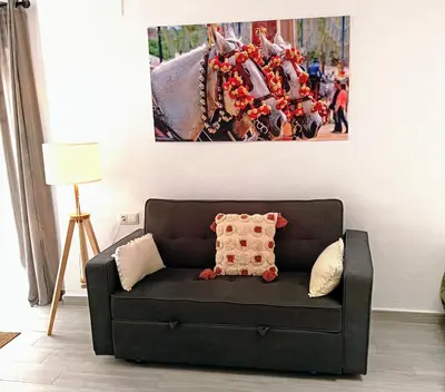 a couch in a living room with a picture on the wall at Apartamentos Turísticos Antonio Parra in Jerez de la Frontera